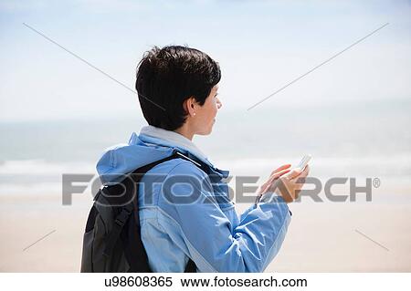 Mid adult woman texting on smartphone from beach whilst looking out to sea View Large Photo Image Stock Photography - Mid adult woman texting on smartphone from beach whilst looking out to sea. Fotosearch