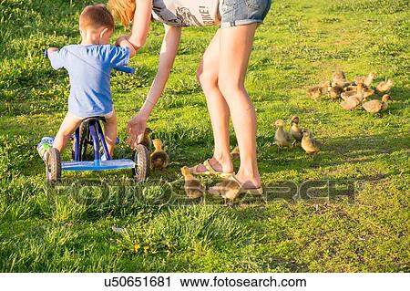 Mother helping son ride on tricycle, rear view View Large Photo Image Stock Image - Mother helping son ride on tricycle, rear view. Fotosearch