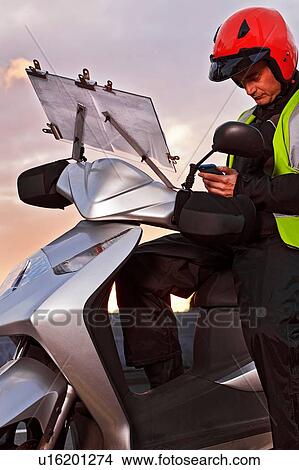 Motor scooter rider, learning the knowledge, using smartphone on city roadside View Large Photo Image Picture - Motor scooter rider, learning the knowledge, using smartphone on city roadside. Fotosearch