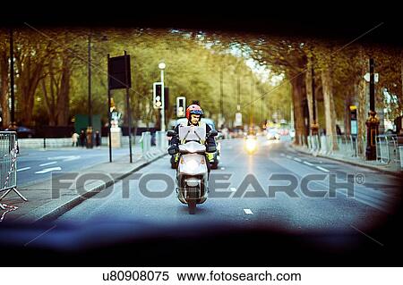 Stock Photography - Motor scooter rider on the move, seen from vehicle. Fotosearch