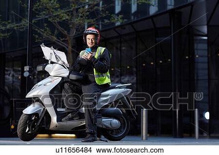 Motor scooter rider reading smartphone in London View Large Photo Image Picture - Motor scooter rider reading smartphone in London. Fotosearch