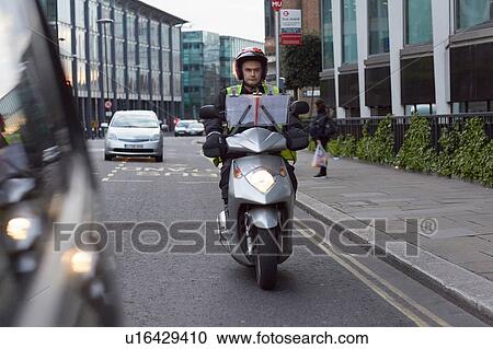 Stock Image - Motor scooter rider, undertaking taxi driver training the knowledge, on the move in London. Fotosearch