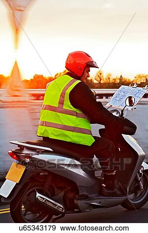 Stock Photo - Motor scooter rider, undertaking taxi driver training the knowledge, on the move in London. Fotosearch