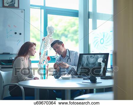Picture - Orthopaedic consultant with patient in consulting room. Fotosearch