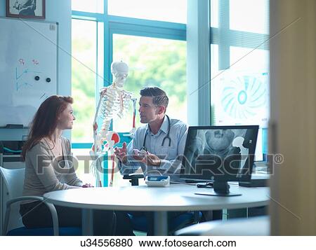 Stock Image - Orthopaedic consultant with patient in consulting room. Fotosearch