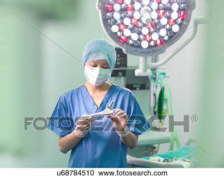 Stock Image - Orthopaedic nurse in operating theatre with replacement hip stem. Fotosearch