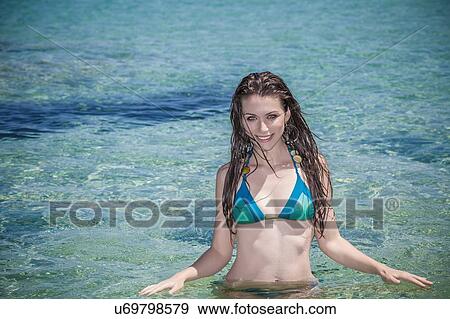 Stock Photo - Portrait of beautiful young woman wading in sea. Fotosearch