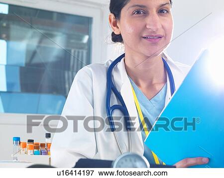 Portrait of female doctor holding medical notes in hospital View Large Photo Image Stock Photo - Portrait of female doctor holding medical notes in hospital. Fotosearch