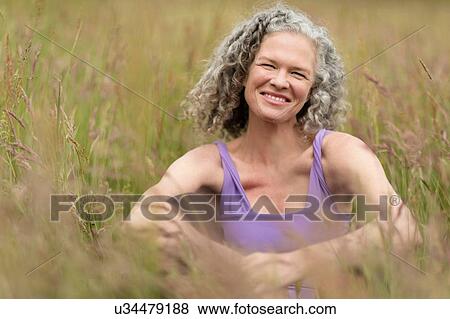 Portrait of mature woman sitting in long grass View Large Photo Image Stock Photo - Portrait of mature woman sitting in long grass. Fotosearch