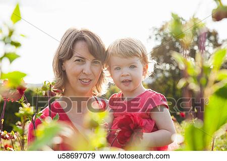Stock Photo - Portrait of mid adult mother and toddler daughter in flower field. Fotosearch