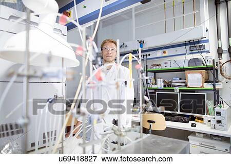 Stock Photo - Portrait of young male scientist behind lab experiment. Fotosearch