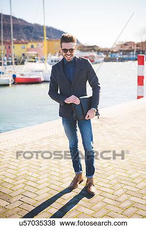 Portrait of young man carrying briefcase on lakeside, Rovato, Brescia, Italy View Large Photo Image Stock Photo - Portrait of young man carrying briefcase on lakeside, Rovato, Brescia, Italy. Fotosearch