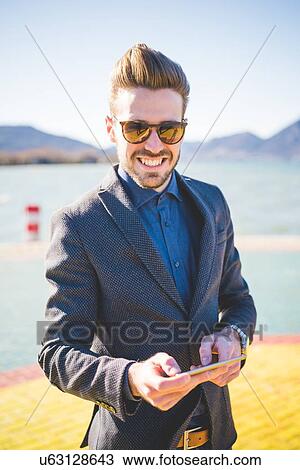 Stock Image - Portrait of young man with digital tablet on lakeside, Rovato, Brescia, Italy. Fotosearch
