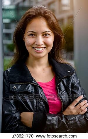 Portrait of young woman with arms folded leaning against pillar View Large Photo Image Stock Image - Portrait of young woman with arms folded leaning against pillar. Fotosearch