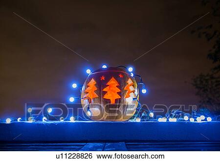Stock Photograph - Pumpkin with Christmas trees carved into it. Fotosearch