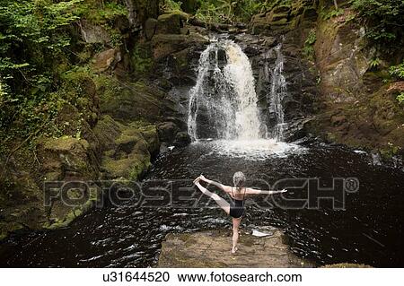 Rear view of mature woman practicing yoga in front of waterfall View Large Photo Image Stock Image - Rear view of mature woman practicing yoga in front of waterfall. Fotosearch