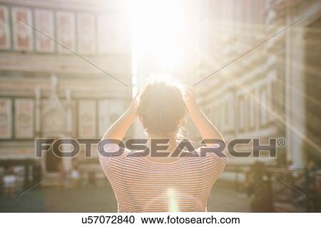 Stock Image - Rear view of mid adult woman, arms raised, lens flare, Duomo Cathedral, Florence, Italy. Fotosearch