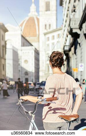 Rear view of mid adult woman holding bicycle looking at Duomo Cathedral, Florence, Italy View Large Photo Image Picture - Rear view of mid adult woman holding bicycle looking at Duomo Cathedral, Florence, Italy. Fotosearch