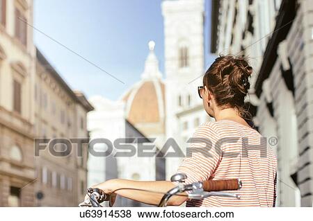 Rear view of mid adult woman holding bicycle looking at Duomo Cathedral, Florence, Italy View Large Photo Image Stock Photo - Rear view of mid adult woman holding bicycle looking at Duomo Cathedral, Florence, Italy. Fotosearch