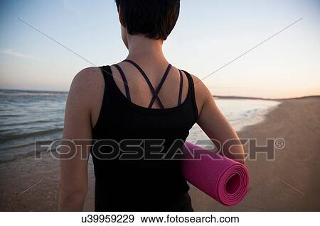 Rear view of mid adult woman preparing for yoga on beach at sunset View Large Photo Image Stock Photo - Rear view of mid adult woman preparing for yoga on beach at sunset. Fotosearch