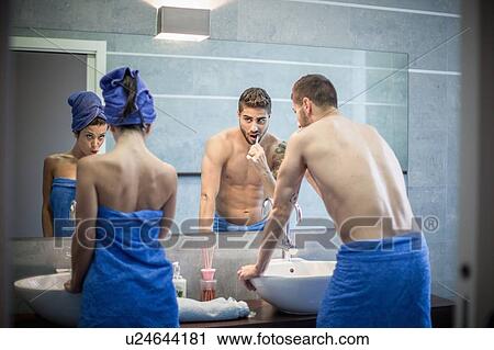 Rear view of young couple brushing teeth in bathroom mirror View Large Photo Image Stock Image - Rear view of young couple brushing teeth in bathroom mirror. Fotosearch