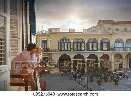Stock Image - Romantic young couple looking out from restaurant balcony in Plaza Vieja, Havana, Cuba. Fotosearch