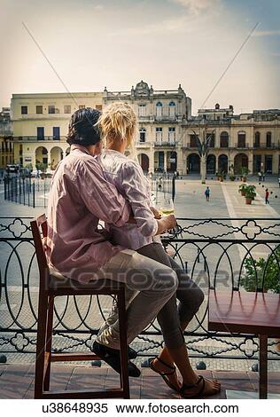 Stock Photography - Romantic young couple looking out from restaurant balcony in Plaza Vieja, Havana, Cuba. Fotosearch