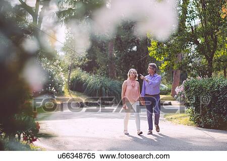 Senior couple outdoors, walking hand in hand, looking at view View Large Photo Image Stock Photography - Senior couple outdoors, walking hand in hand, looking at view. Fotosearch