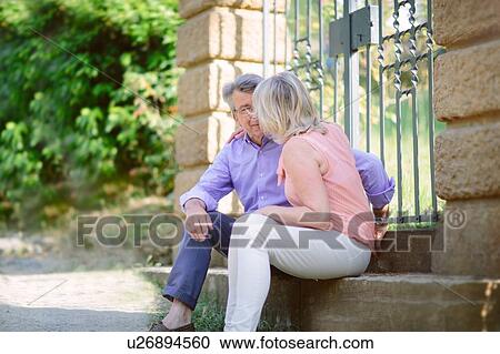 Stock Image - Senior couple sitting on step, face to face. Fotosearch