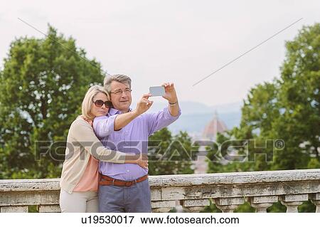 Senior couple taking self portrait, using smartphone View Large Photo Image Stock Photo - Senior couple taking self portrait, using smartphone. Fotosearch