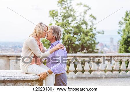 Senior woman sitting on wall, kissing senior man View Large Photo Image Stock Photo - Senior woman sitting on wall, kissing senior man. Fotosearch