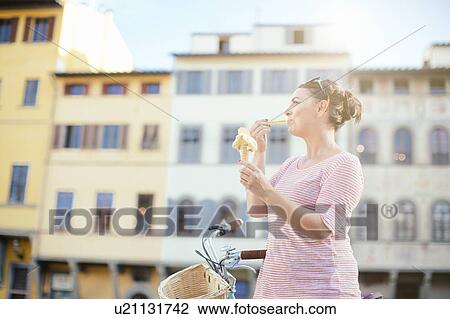 Side view of mid adult woman eating ice cream cone, looking away View Large Photo Image Stock Image - Side view of mid adult woman eating ice cream cone, looking away. Fotosearch