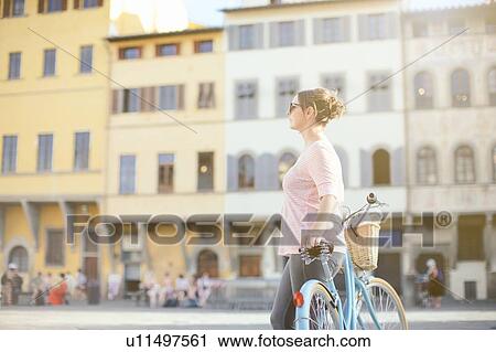 Side view of mid adult woman leaning against bicycle looking away View Large Photo Image Stock Image - Side view of mid adult woman leaning against bicycle looking away. Fotosearch