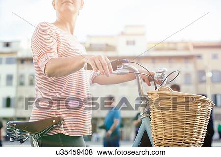 Side view of mid section of mid adult woman holding cycle View Large Photo Image Stock Photo - Side view of mid section of mid adult woman holding cycle. Fotosearch