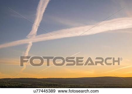 Silhouetted hillside view of sunset sky with criss crossing vapour trails View Large Photo Image Stock Photo - Silhouetted hillside view of sunset sky with criss crossing vapour trails. Fotosearch