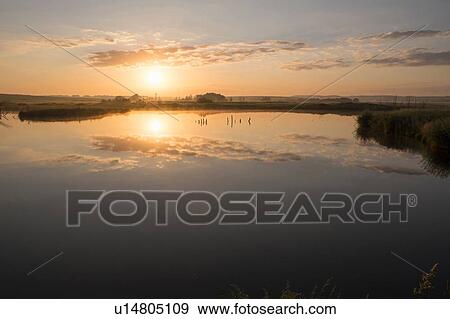 Stock Photo - Silhouetted view of still lake at sunset. Fotosearch