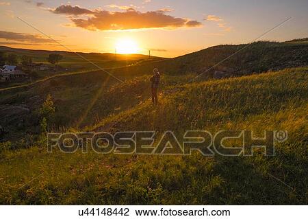 Silhouetted woman looking out from hilly field at sunset View Large Photo Image Stock Image - Silhouetted woman looking out from hilly field at sunset. Fotosearch