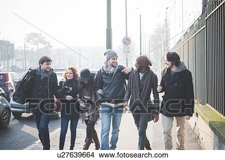 Six young adult friends chatting whilst strolling along city street View Large Photo Image Picture - Six young adult friends chatting whilst strolling along city street. Fotosearch