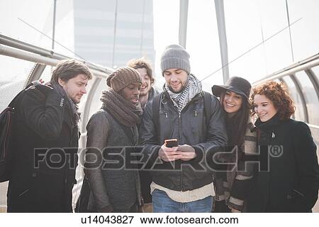 Stock Photo - Six young adult friends on footbridge reading smartphone text. Fotosearch