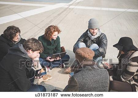 Six young adult friends sitting networking on smartphones View Large Photo Image Stock Photo - Six young adult friends sitting networking on smartphones. Fotosearch
