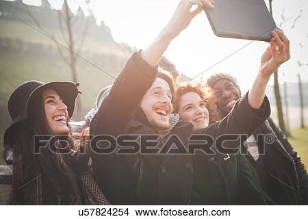 Six young adult friends taking digital tablet selfie in park View Large Photo Image Picture - Six young adult friends taking digital tablet selfie in park. Fotosearch