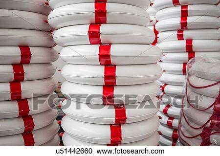 Stock Image - Stack of life buoys in factory that produces products for boating and camping. Fotosearch