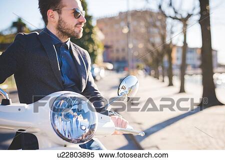 Stylish young man looking out from moped View Large Photo Image Stock Photography - Stylish young man looking out from moped. Fotosearch