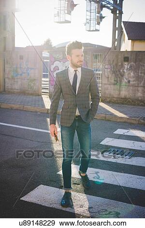 Stock Photo - Stylish young man walking on pedestrian crossing. Fotosearch