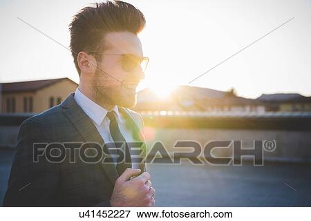 Stock Photo - Stylish young man wearing shades in sunlight. Fotosearch