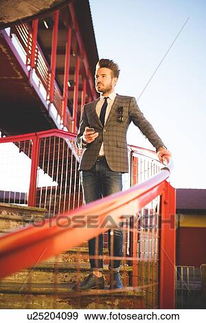 Stylish young man with smartphone looking out from footbridge View Large Photo Image Stock Photo - Stylish young man with smartphone looking out from footbridge. Fotosearch