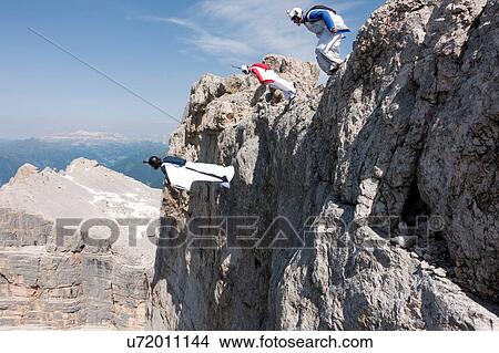 Three male BASE jumpers exiting from mountain top, Dolomites, Italy View Large Photo Image Picture - Three male BASE jumpers exiting from mountain top, Dolomites, Italy. Fotosearch