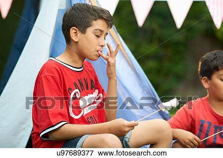 Two brothers eating toasted marshmallows in garden View Large Photo Image Stock Photo - Two brothers eating toasted marshmallows in garden. Fotosearch