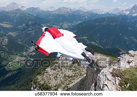 Picture - Two male BASE jumpers exiting from mountain top, Dolomites, Italy. Fotosearch