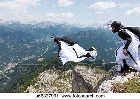 Stock Image - Two male BASE jumpers exiting from mountain top, Dolomites, Italy. Fotosearch